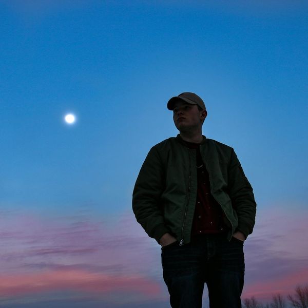 Person stretching outdoors during a sunrise, silhouette style with blue sky.